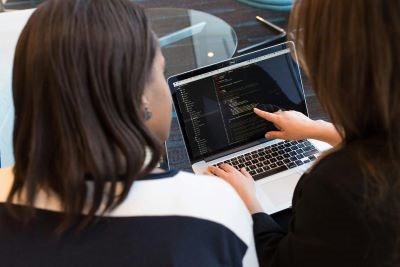 two women sitting and pointing at a computer screen