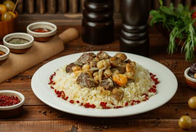 a dish of plov with rice, lamb, and vegetables