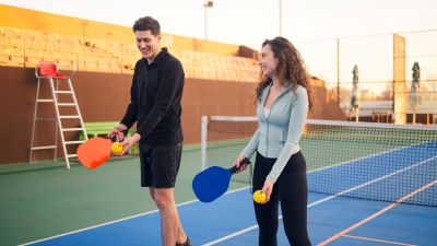 two younger people playing pickleball