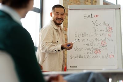 person at whiteboard writing words in Spanish