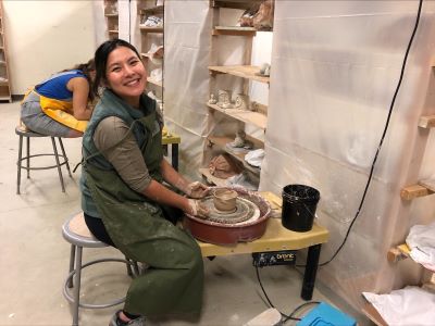 Student sitting at a pottery wheel