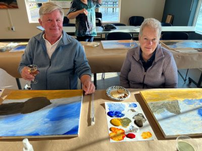 an elderly couple painting, drinking, and smiling