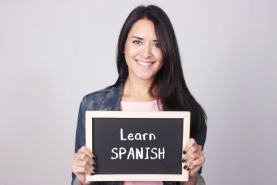 woman holding a sign that says hello in Spanish