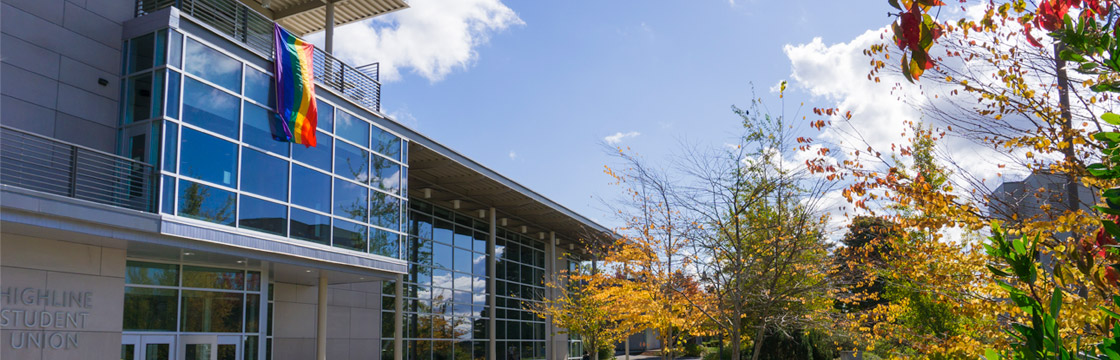 Photo of rainbow flag hanging from Highline College Student Union building during LGBTQIA history month.